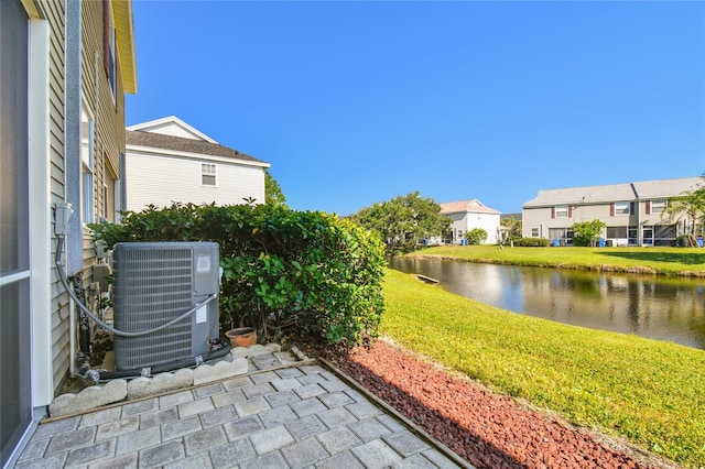 view of yard with a residential view, central air condition unit, and a water view