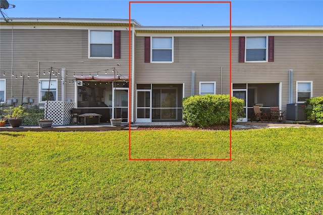 rear view of property with a lawn, central AC, and a sunroom