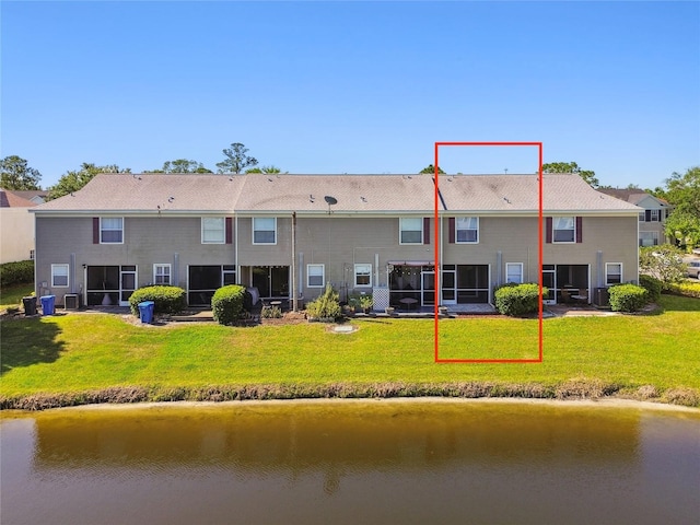 rear view of house with a yard and a water view