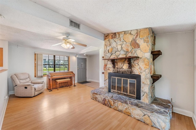 15808 Willowdale Rd, Tampa, FL 33625 - living room featuring a textured ceiling, wood finished floors, ceiling fan, and a stone fireplace