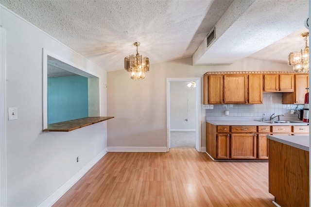 15808 Willowdale Rd, Tampa, FL 33625 - kitchen with a chandelier, light wood-type flooring, backsplash, brown cabinetry, and a textured ceiling