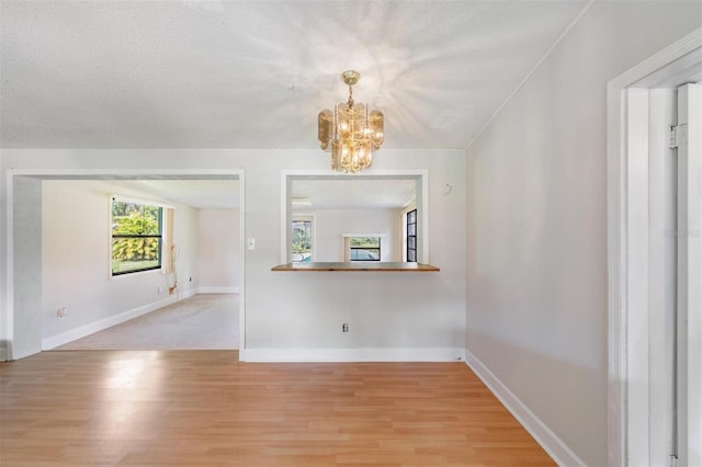 15808 Willowdale Rd, Tampa, FL 33625 - unfurnished room with light wood-type flooring, a chandelier, and a textured ceiling
