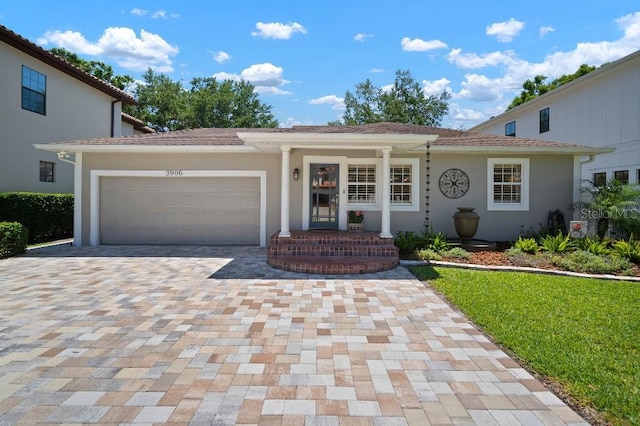 view of front of house featuring stucco siding, decorative driveway, and a garage