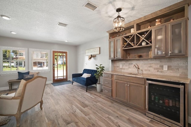 bar featuring beverage cooler, light wood-style flooring, wet bar, and a sink