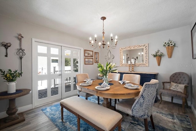 dining space featuring baseboards, wood finished floors, a notable chandelier, and french doors