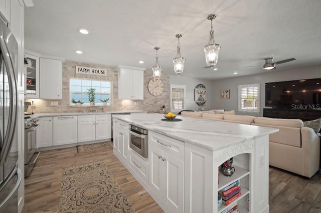 kitchen featuring a center island, appliances with stainless steel finishes, open floor plan, and decorative backsplash