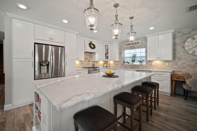 kitchen with white cabinetry, backsplash, dark wood-style flooring, and appliances with stainless steel finishes