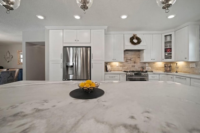 kitchen with white cabinetry, stainless steel appliances, glass insert cabinets, and decorative backsplash