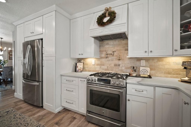 kitchen with stainless steel appliances, light wood-style floors, white cabinetry, premium range hood, and a textured ceiling