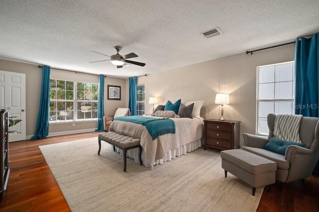 bedroom featuring a textured ceiling, visible vents, ceiling fan, and wood finished floors