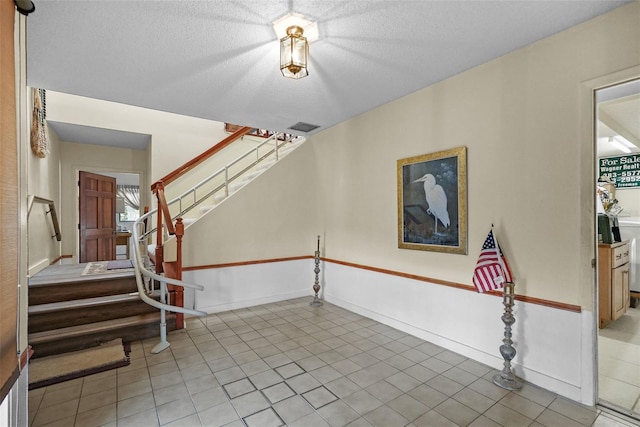 foyer with light tile patterned flooring, visible vents, and stairway