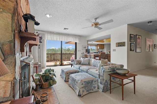 living area featuring carpet floors, a textured ceiling, ceiling fan, and visible vents