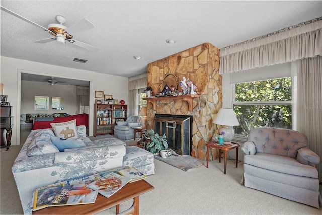 carpeted living room featuring a wealth of natural light, a fireplace, a ceiling fan, and visible vents