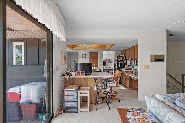 interior space featuring light colored carpet, light countertops, a breakfast bar area, brown cabinetry, and a peninsula