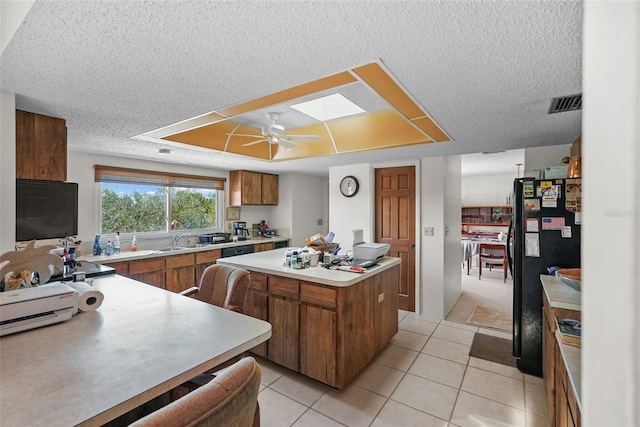 kitchen featuring a kitchen island, a textured ceiling, visible vents, light countertops, and freestanding refrigerator