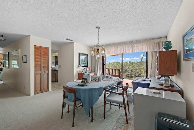 dining room featuring a textured ceiling, a notable chandelier, visible vents, and light carpet