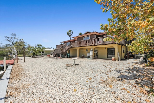view of front of property featuring a wooden deck, stucco siding, and stairway