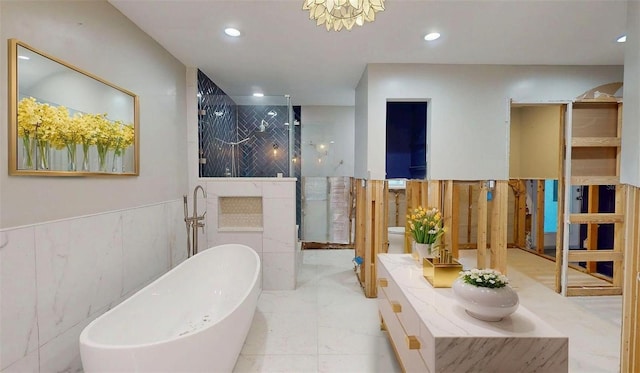 4511 Huntington St NE, Saint Petersburg, FL 33703 - bathroom featuring a soaking tub, a stall shower, double vanity, recessed lighting, and a wainscoted wall