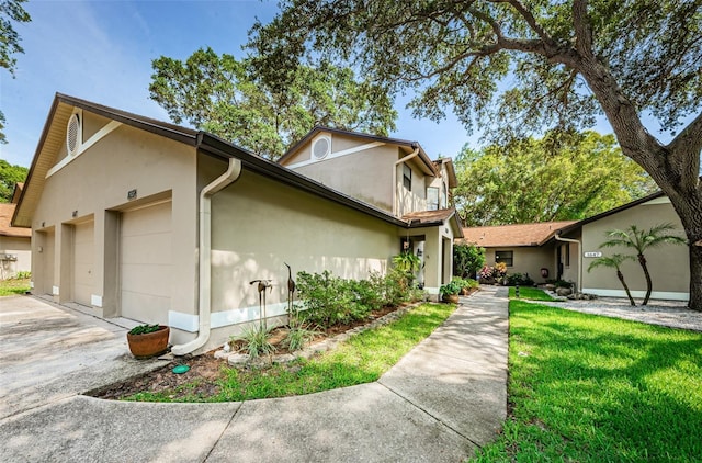 view of front of property with stucco siding, an attached garage, driveway, and a front lawn