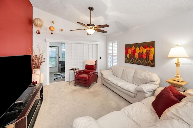 carpeted living room with a textured ceiling, ceiling fan, a healthy amount of sunlight, and lofted ceiling