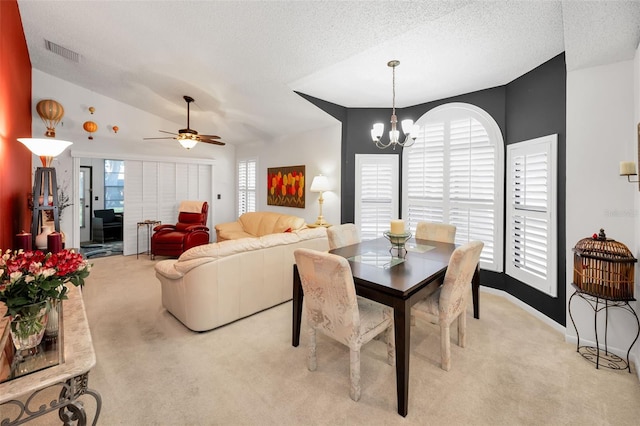 dining room with light colored carpet, a textured ceiling, ceiling fan with notable chandelier, lofted ceiling, and visible vents