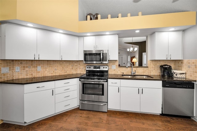 kitchen with a sink, dark countertops, stainless steel appliances, and a notable chandelier