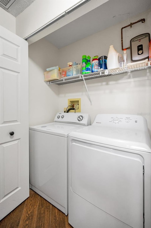 clothes washing area featuring laundry area, wood finished floors, and washer and dryer