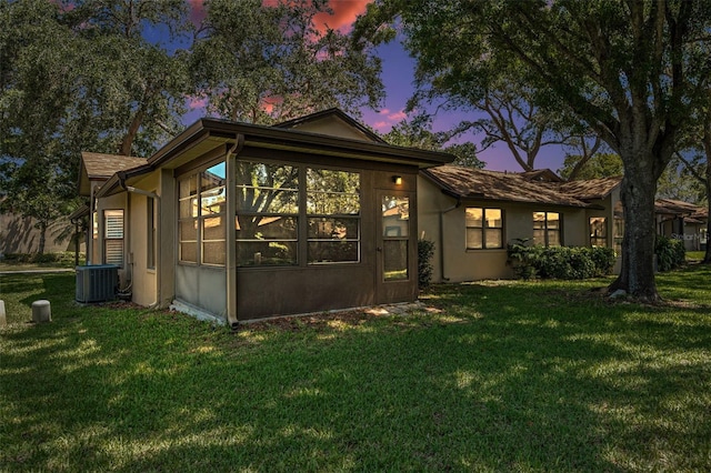 view of home's exterior with a sunroom, a yard, and central AC