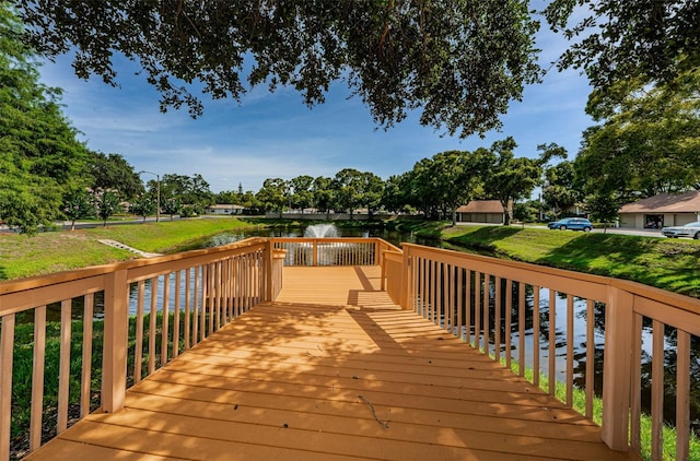 wooden terrace with a water view and a yard