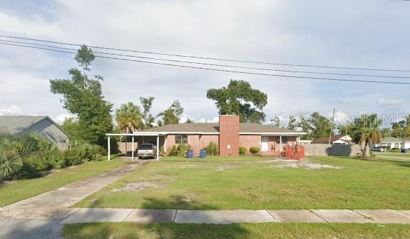 view of front facade with driveway, a front yard, and an attached carport