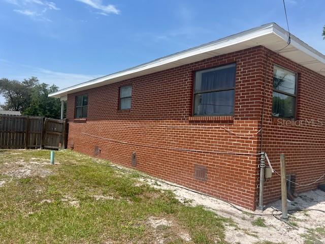 view of home's exterior with fence and brick siding