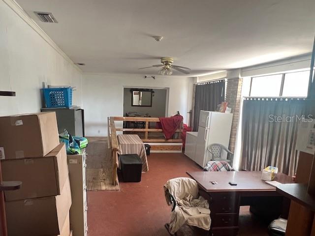 interior space featuring visible vents, crown molding, and freestanding refrigerator