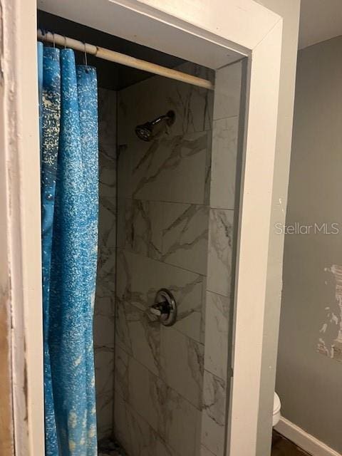 full bathroom featuring toilet, a shower stall, and baseboards