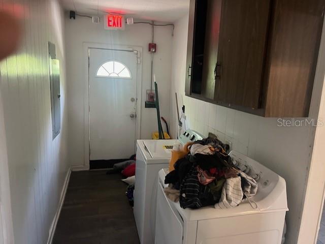 clothes washing area featuring washing machine and dryer, cabinet space, dark wood-style flooring, and baseboards