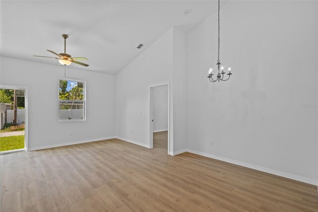 7603 Rhode Island Dr, Tampa, FL 33619 - interior space featuring visible vents, baseboards, light wood finished floors, high vaulted ceiling, and ceiling fan with notable chandelier