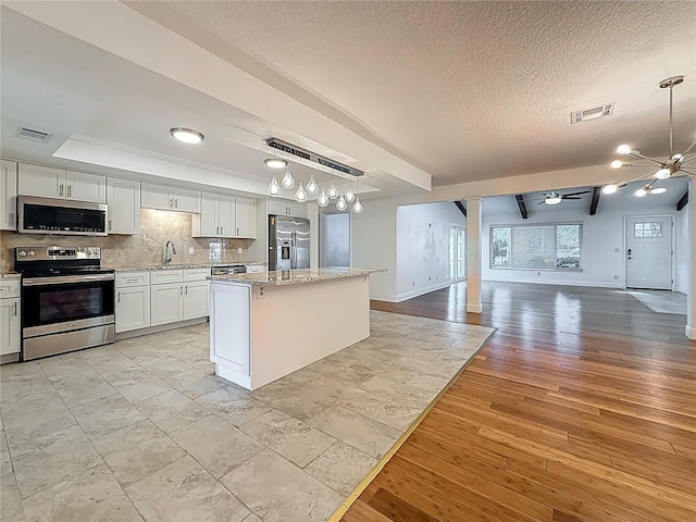 13891 Feather Sound Dr, Clearwater, FL 33762 - kitchen with stainless steel appliances, open floor plan, a ceiling fan, a center island, and a textured ceiling