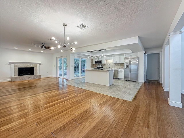 13891 Feather Sound Dr, Clearwater, FL 33762 - kitchen featuring stainless steel appliances, open floor plan, a chandelier, light wood-style flooring, and a textured ceiling