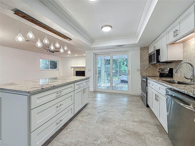 13891 Feather Sound Dr, Clearwater, FL 33762 - kitchen featuring stainless steel appliances, a tray ceiling, decorative backsplash, light stone countertops, and a fireplace