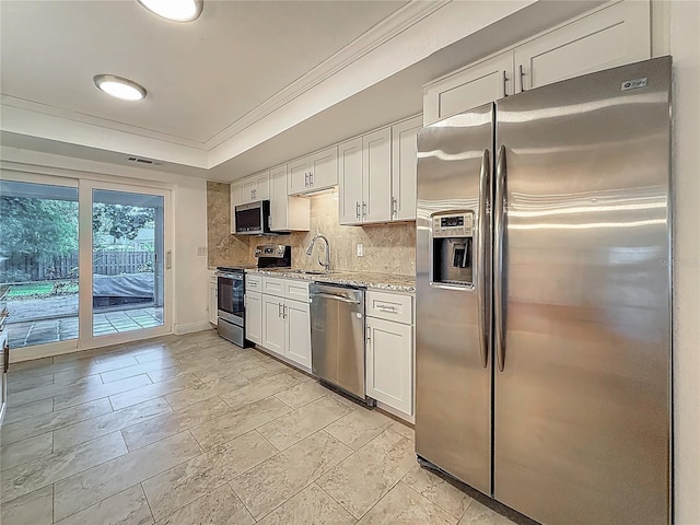 13891 Feather Sound Dr, Clearwater, FL 33762 - kitchen featuring appliances with stainless steel finishes, ornamental molding, white cabinets, tasteful backsplash, and light stone counters