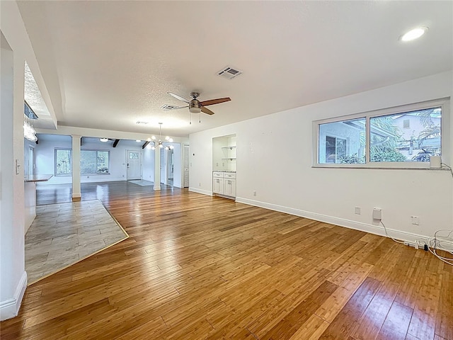 13891 Feather Sound Dr, Clearwater, FL 33762 - unfurnished living room featuring ornate columns, hardwood / wood-style floors, a chandelier, and ceiling fan