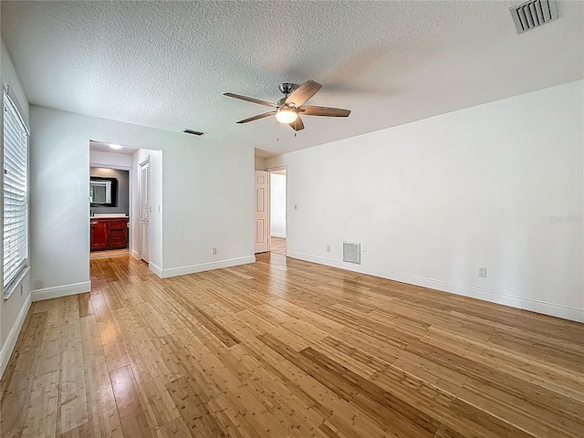 13891 Feather Sound Dr, Clearwater, FL 33762 - unfurnished bedroom with light wood-type flooring, a textured ceiling, ensuite bathroom, and ceiling fan