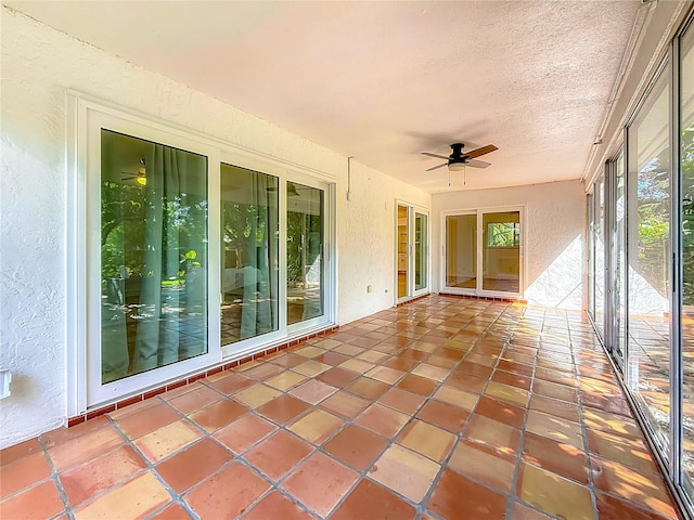 13891 Feather Sound Dr, Clearwater, FL 33762 - unfurnished sunroom featuring a textured wall, a ceiling fan, a textured ceiling, and tile patterned flooring