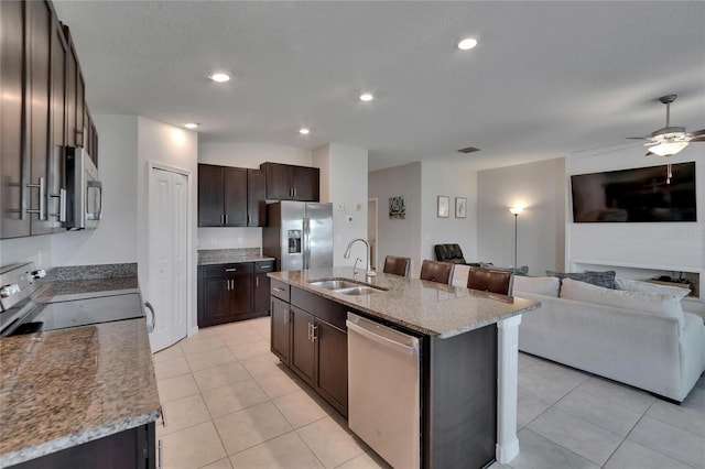 13506 Wild Ginger St, Riverview, FL 33579 - kitchen featuring appliances with stainless steel finishes, open floor plan, dark brown cabinets, light tile patterned floors, and light stone counters