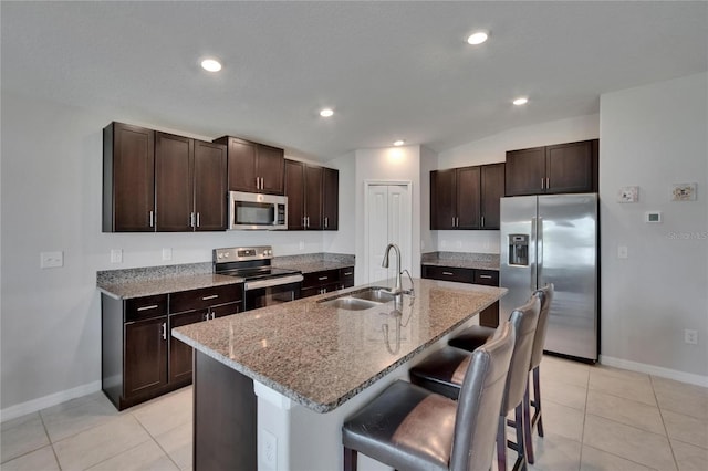 13506 Wild Ginger St, Riverview, FL 33579 - kitchen with appliances with stainless steel finishes, a breakfast bar area, dark brown cabinets, light stone counters, and light tile patterned floors