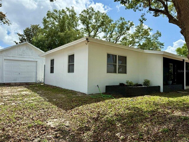 1505 Piedmont Dr, Deltona, FL 32725 - view of home's exterior with a garage, stucco siding, an outdoor structure, and driveway