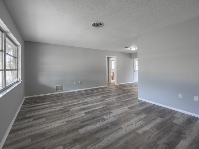 unfurnished room featuring wood finished floors, visible vents, and a textured ceiling