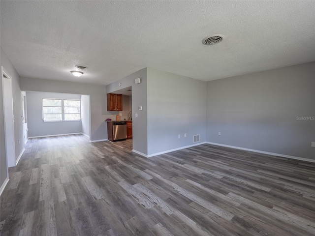 unfurnished living room featuring a textured ceiling, dark wood-style flooring, and visible vents