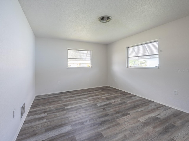 spare room featuring a wealth of natural light, wood finished floors, and visible vents