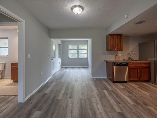 kitchen with wood finished floors, a textured ceiling, stainless steel appliances, baseboards, and visible vents