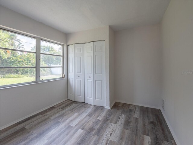 unfurnished bedroom with wood finished floors, a closet, and baseboards